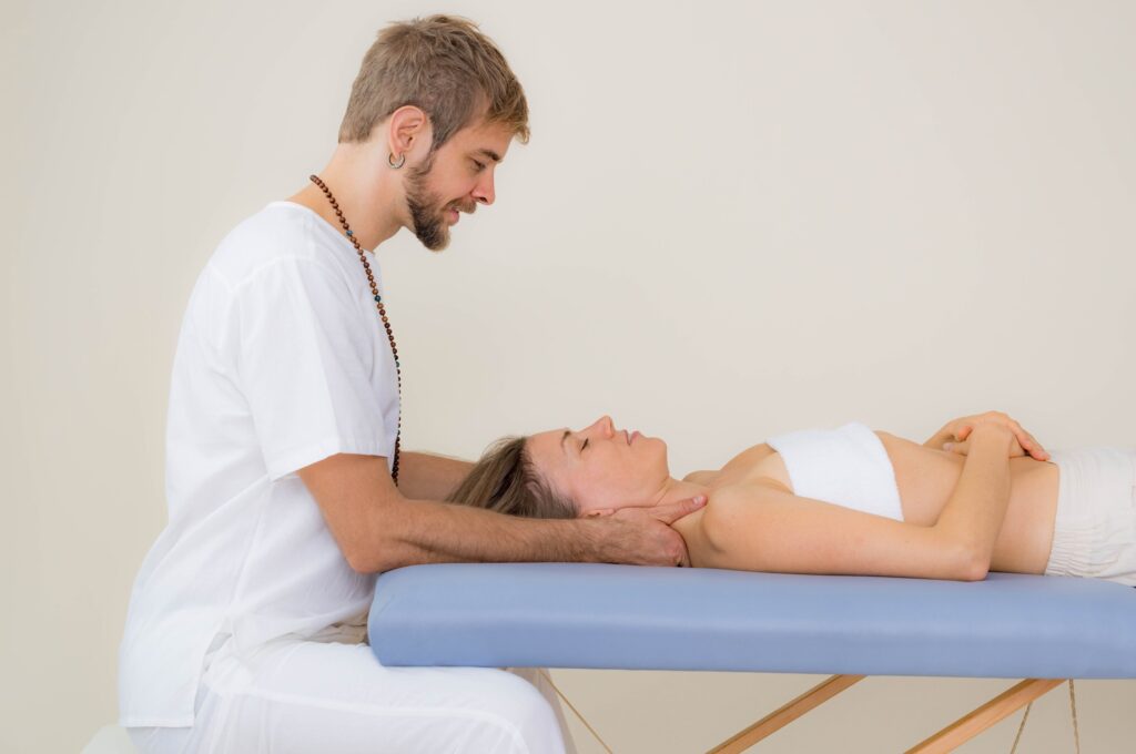 Massage therapist gives a shoulder massage to a woman laying on a light blue massage table.