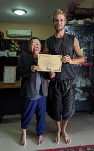 Teacher and student standing side by side holding a certificate of a Chi Nei Tsang education.